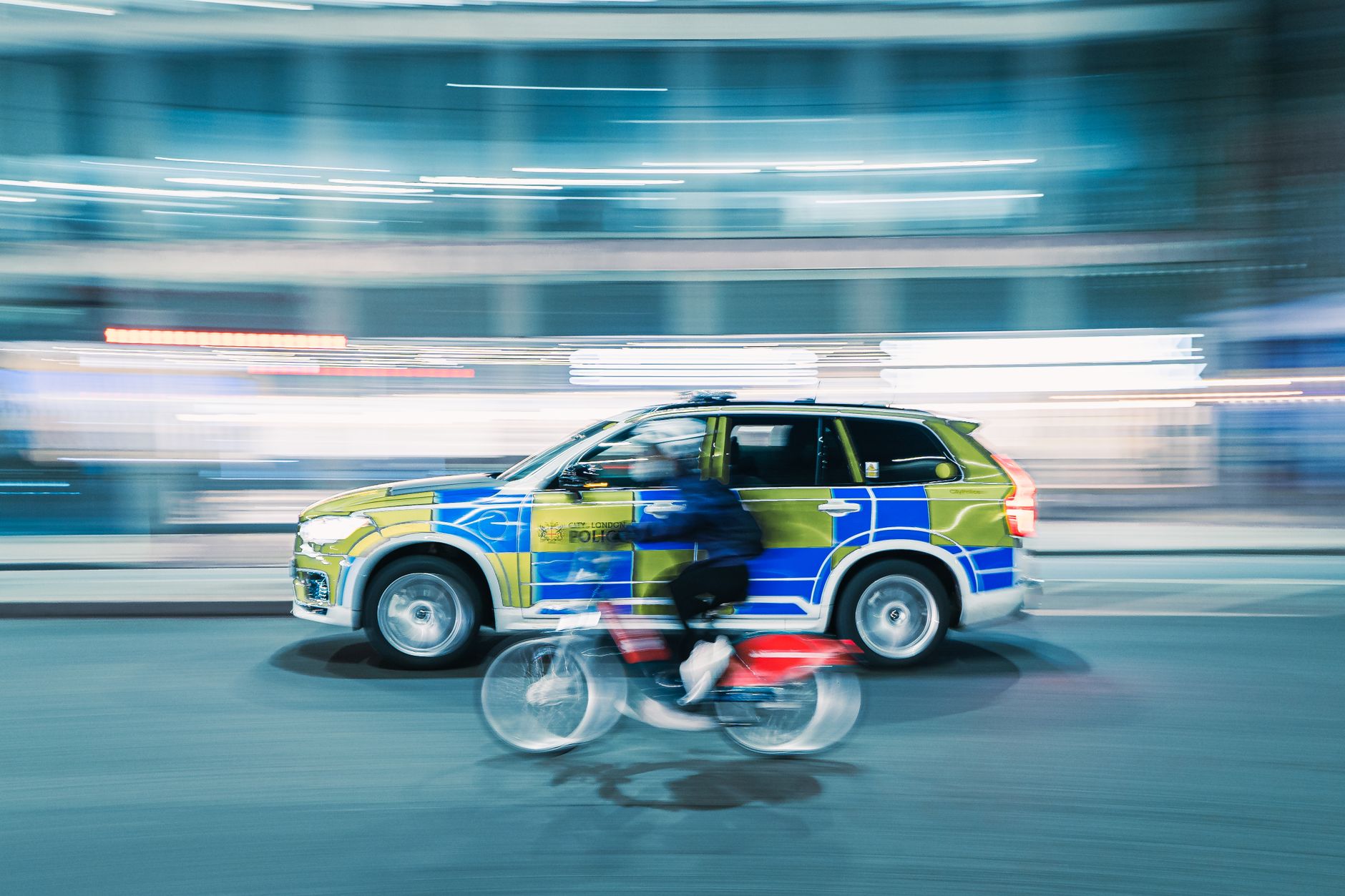 a person riding a bicycle and a fast car on the road